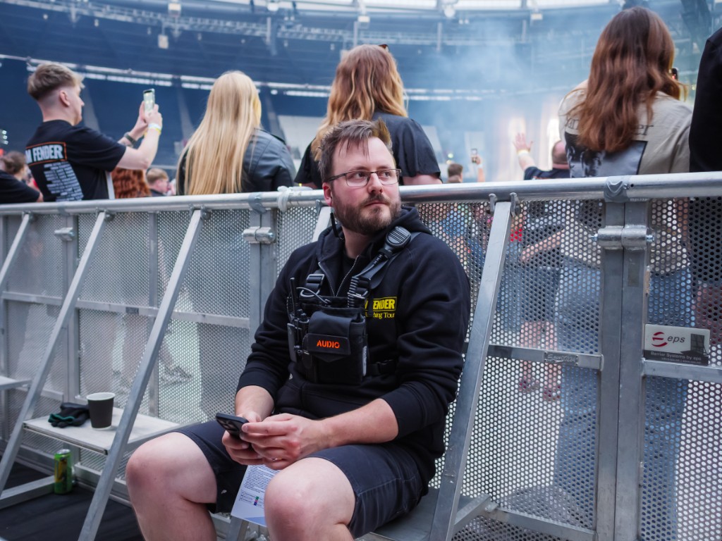 Joe Baker on site at a live event, wearing a continuous glucose monitor while working on a production